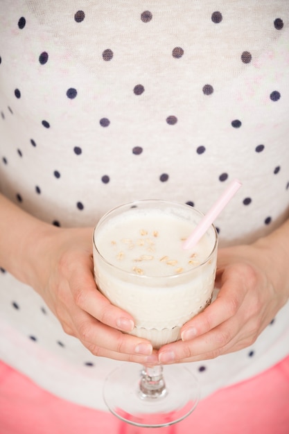 Ragazza in una camicetta a pois con un bicchiere di frullato sano servito con paglia e farina d'avena