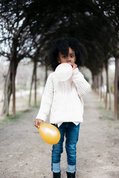 Girl blowing balloon outside