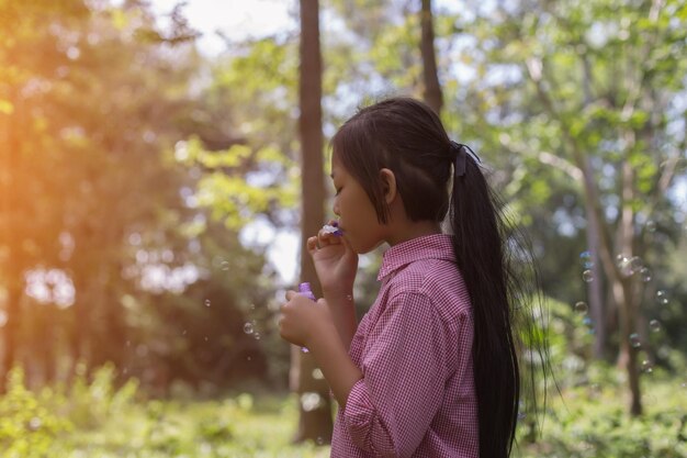 Photo girl blowing bubbles while standing against trees