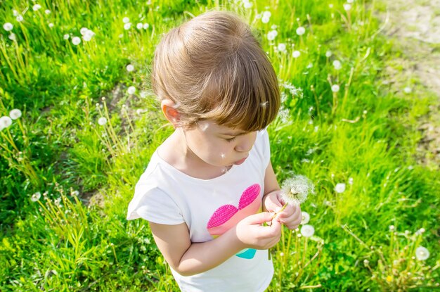 Girl blowing dandelions in the air selective focus