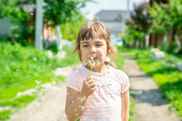 Girl blowing dandelions in the air selective focus