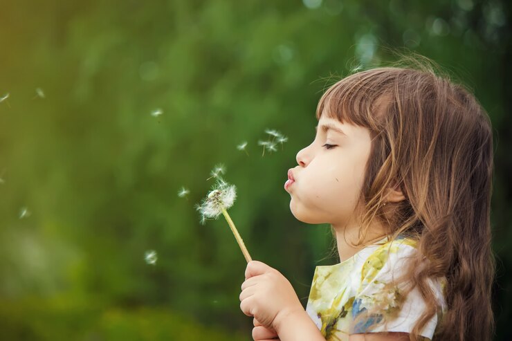 Photo girl blowing dandelions in the air. selective focus.