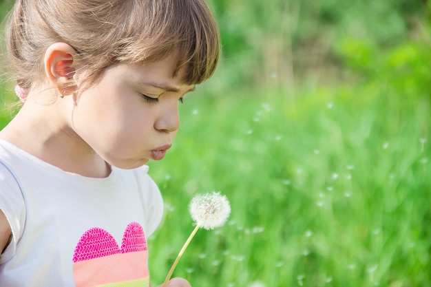 Photo girl blowing dandelions in the air.