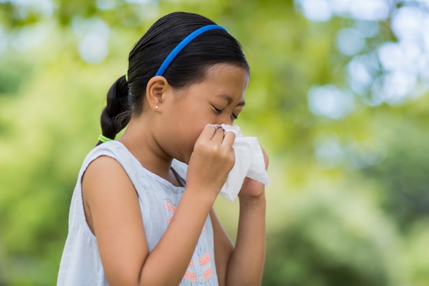 Girl blowing her nose with handkerchief while sneezing