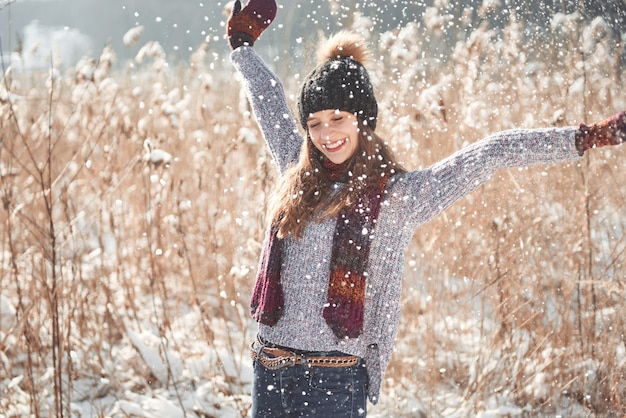 凍るような冬の公園屋外で雪を吹く少女。