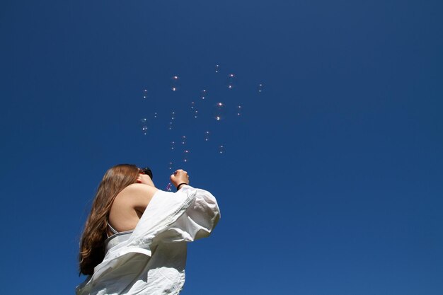 写真 青い空にソープの泡を吹く女の子