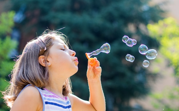 Girl blowing soap bubbles in park in a sunny day