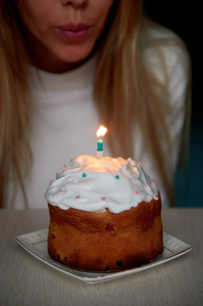 A girl blows out a burning candle on a festive cake for birthday