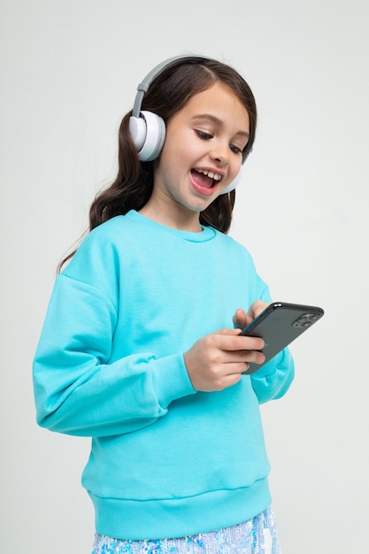 La ragazza in una camicia blu si rilassa con la musica in grandi cuffie alla moda