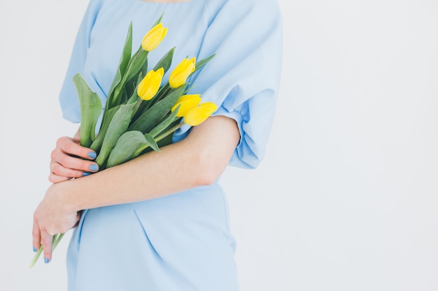 Girl in a blue dress holds a bouquet of yellow tulips