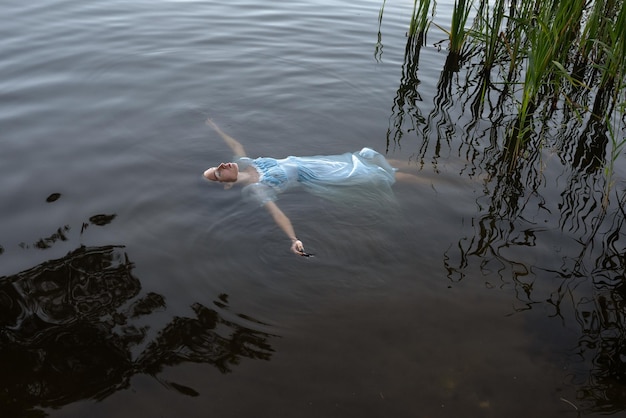 Una ragazza con un vestito blu sotto l'acqua suicidio di una donna sul lago