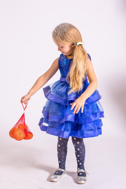 Girl in a blue dress with tangerines on a white background