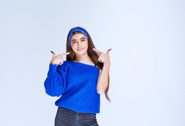 Girl in blue shirt pointing at herself.