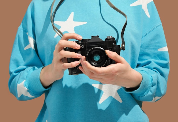 Ragazza in felpa blu con stelle tiene in mano una macchina fotografica retrò viaggia e scatta foto per la memoria