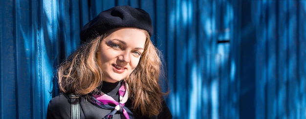 The girl at the blue wall in beret and skirt, Stylish frenchwoman in the shadow of the city