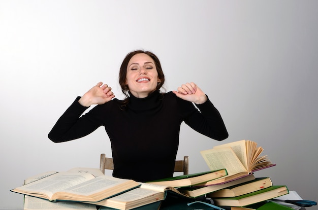 девушка книги экзамен черный свитер трудности учит за столом усталый радуется эмоции