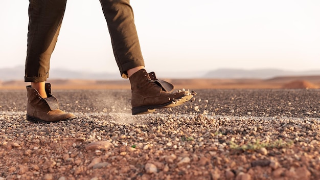 A girl in boots walks and digs small stones on the road. Body part - legs