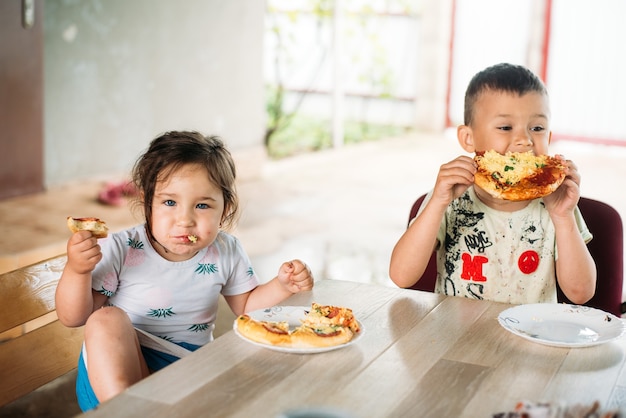 A girl and a boy, children on the street eat mini pizza very appetizing