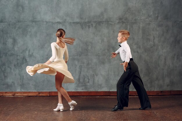 Photo girl and boy dancing against wall