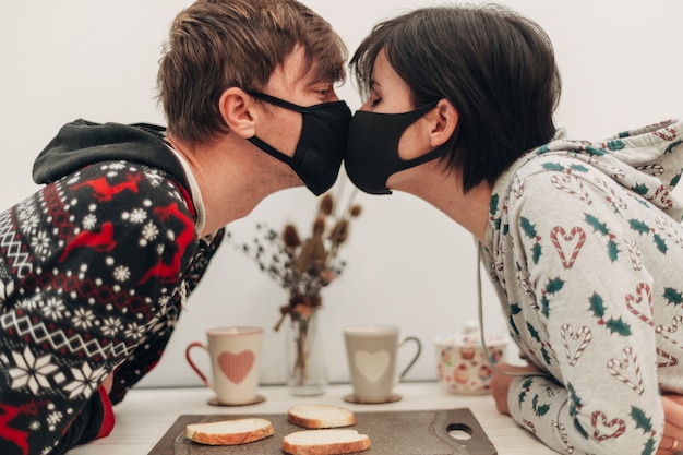 Foto ragazza e ragazzo che si baciano in maschera durante la quarantena del coronavirus.