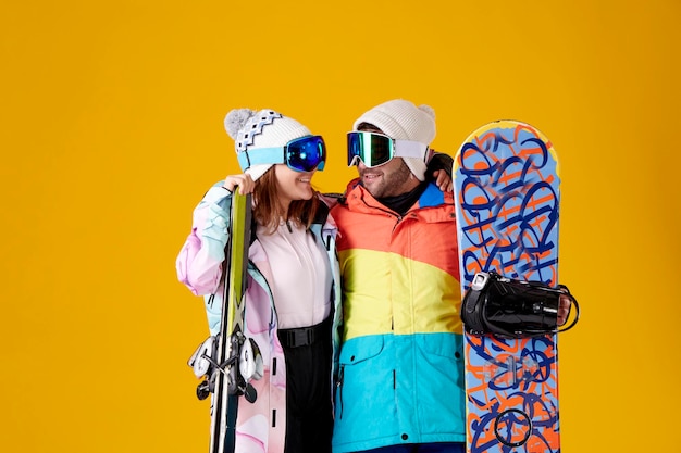 Girl and boy looking at each other with a snowboard and skis