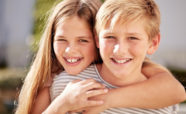 Girl boy and portrait in family smile and happy siblings in home backyard garden and hug together Kids brother and sister with love bonding and care in summer sunshine outdoor and happiness