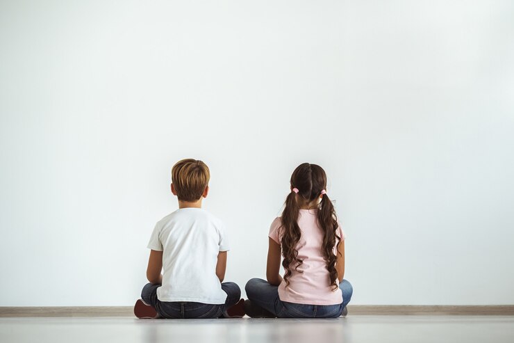 白い壁の背景の床に座っている女の子と男の子
