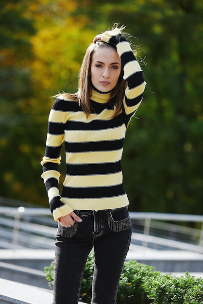 A girl in branded clothes is walking in an autumn park