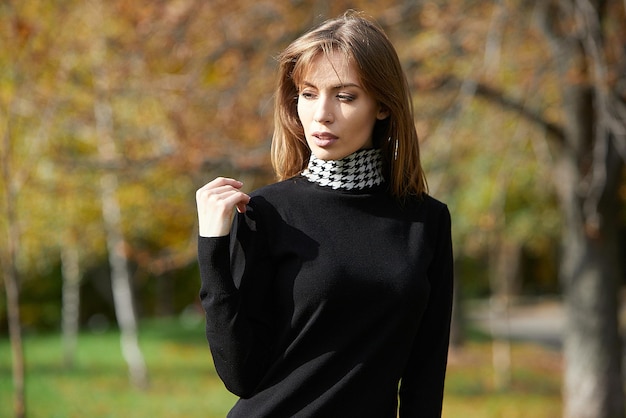 A girl in branded clothes is walking in an autumn park