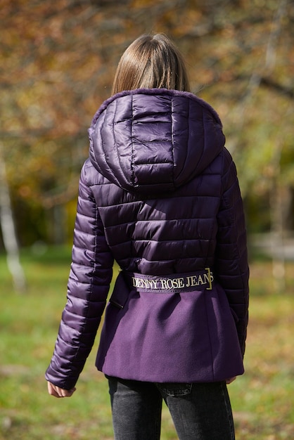 A girl in branded clothes is walking in an autumn park