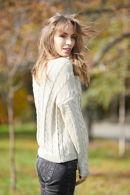 A girl in branded clothes is walking in an autumn park