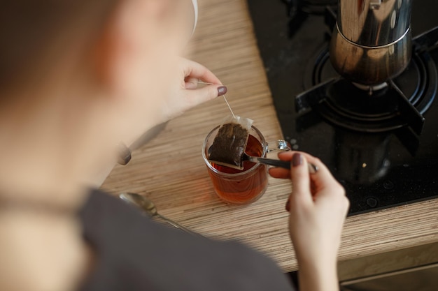 The girl brews tea from a bag in a transparent mug