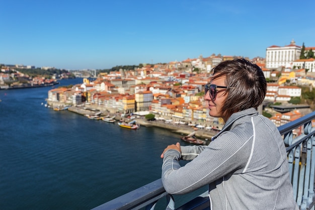 La ragazza sul ponte di san luis nella città portoghese di porto. guarda il paesaggio.