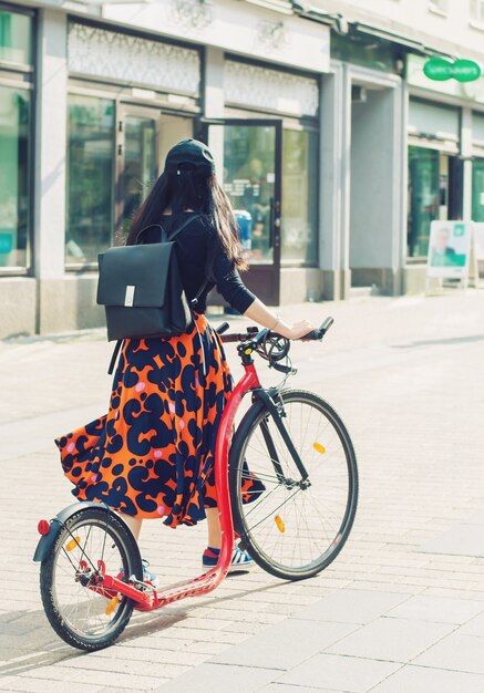 Una ragazza in abiti luminosi e una bicicletta su una strada cittadina, jyvaskyla, finland