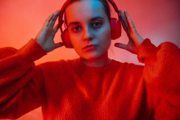 Photo a girl in bright colored lighting listens to music with headphones