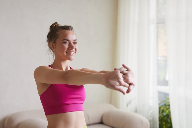 A girl in bright sportswear does exercises for her hands the concept of doing sports at home