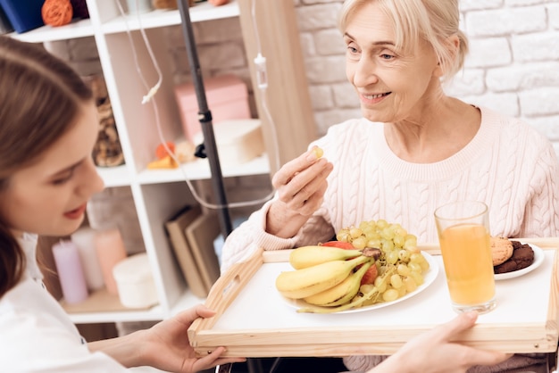 女の子はトレイに朝食をもたらします。女性が食べています。