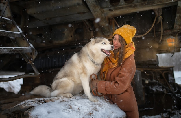 Girl in brown coat and next to sits dog husky