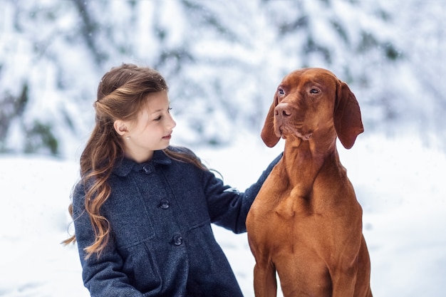 girl and brown dog in nature in winter