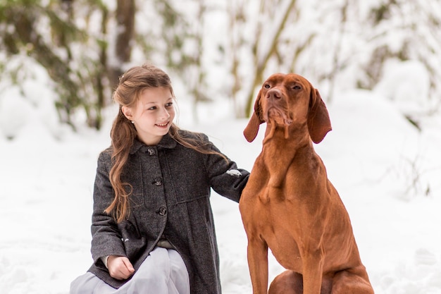 girl and brown dog in nature in winter