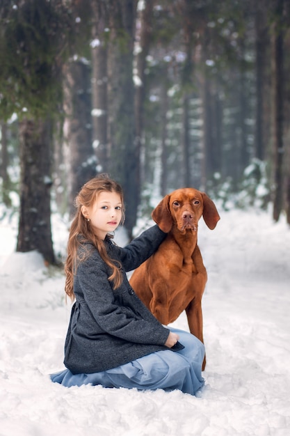 Ragazza e cane marrone in natura in inverno