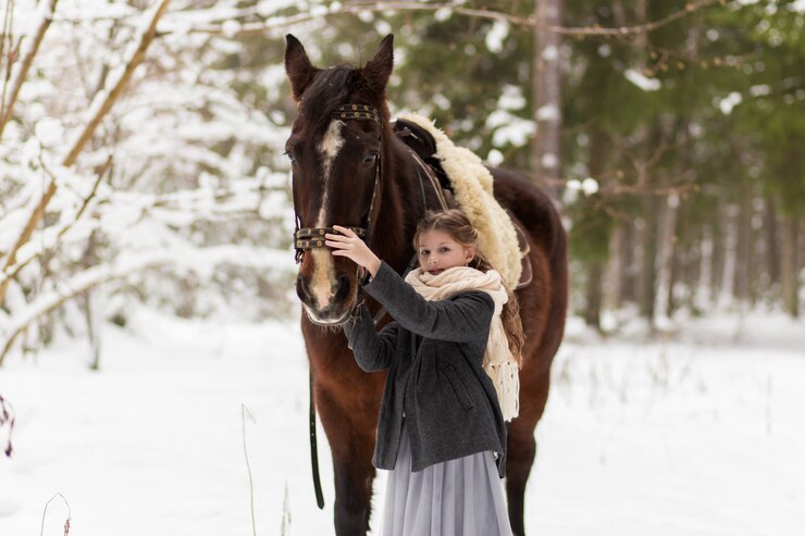 自然の中で冬の少女と茶色の馬