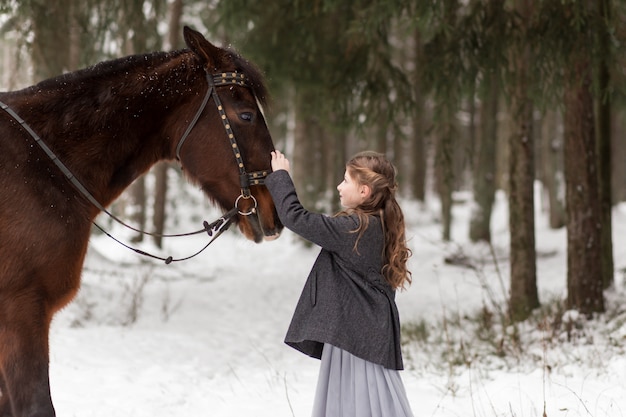 girl and brown horse in winter in nature