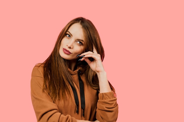 Girl in a brown sweater on a pink background