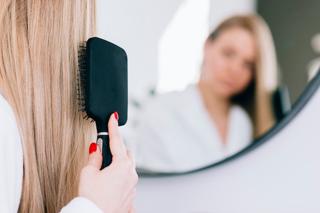 Girl brushing her hair at the bathroom