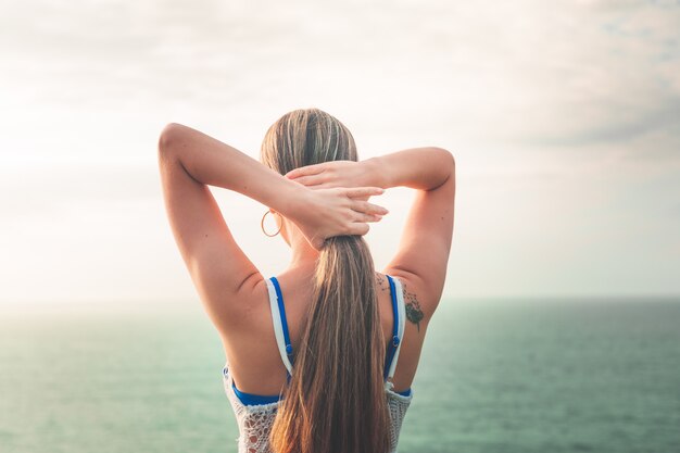 Girl brushing her hair at the coast side