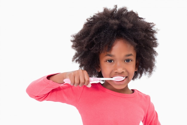 Girl brushing her teeth against a white background