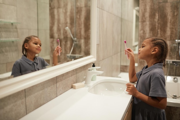 Girl Brushing Teeth by Mirror