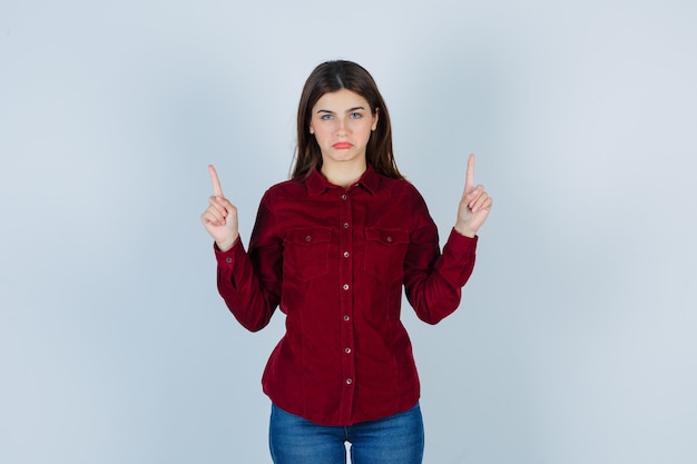 girl in burgundy blouse pointing up and looking dissatisfied