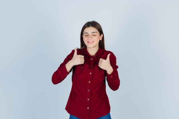 girl in burgundy shirt showing double thumbs up and looking merry